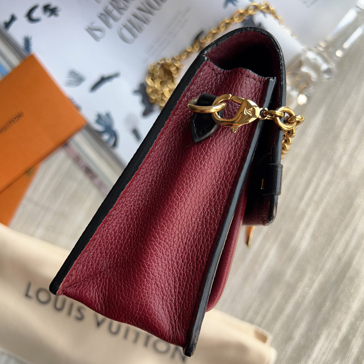 Red leather handbag with gold chain on a blurred background