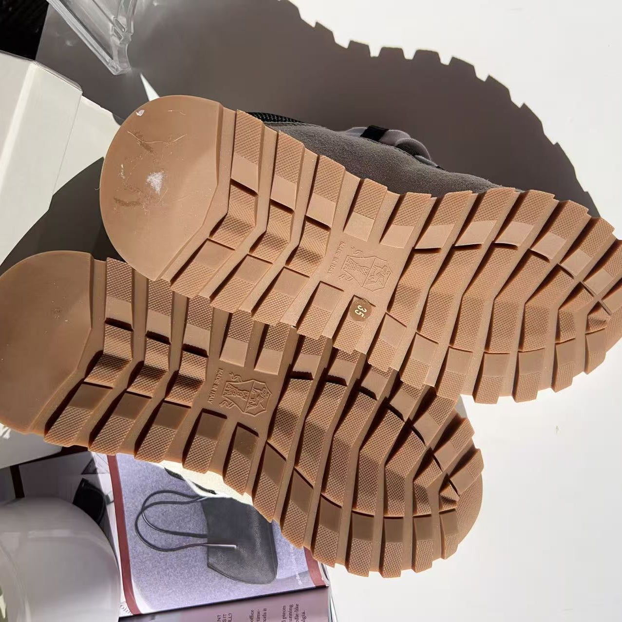 Close-up of a brown boot sole with tread pattern on a white surface.