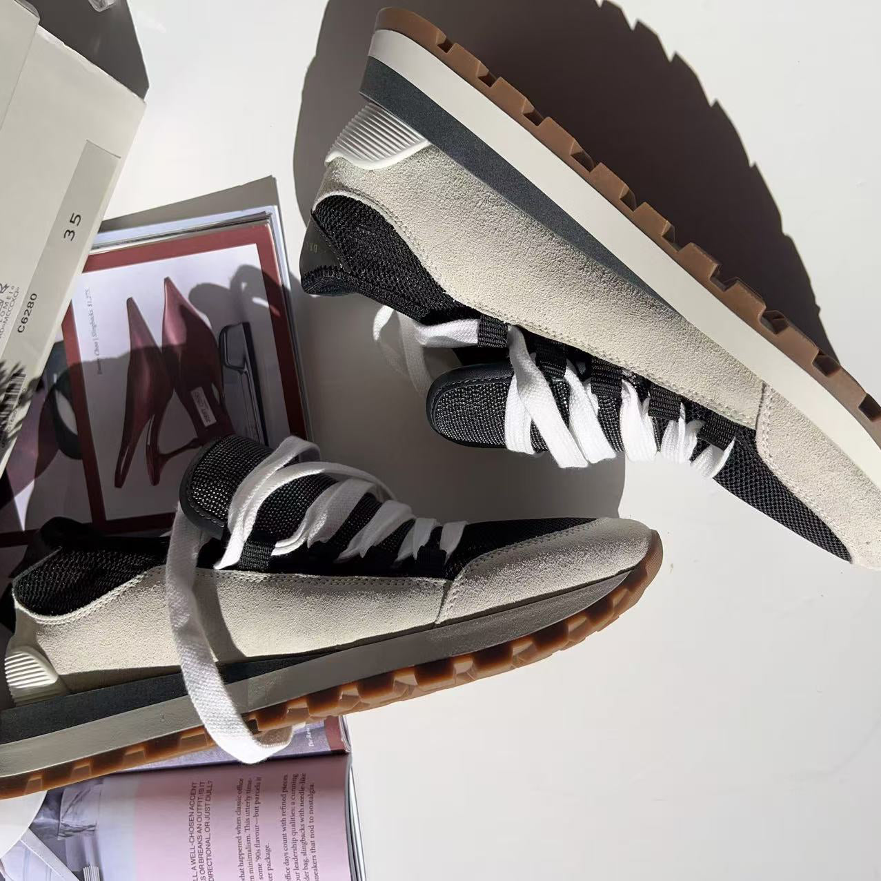Pair of black and white sneakers with brown soles on a white surface.