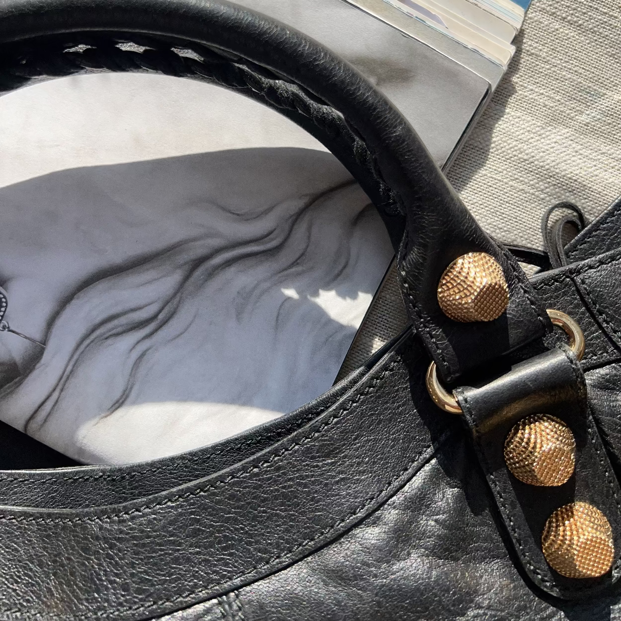 Close-up of a black leather bag with gold studs on a textured surface