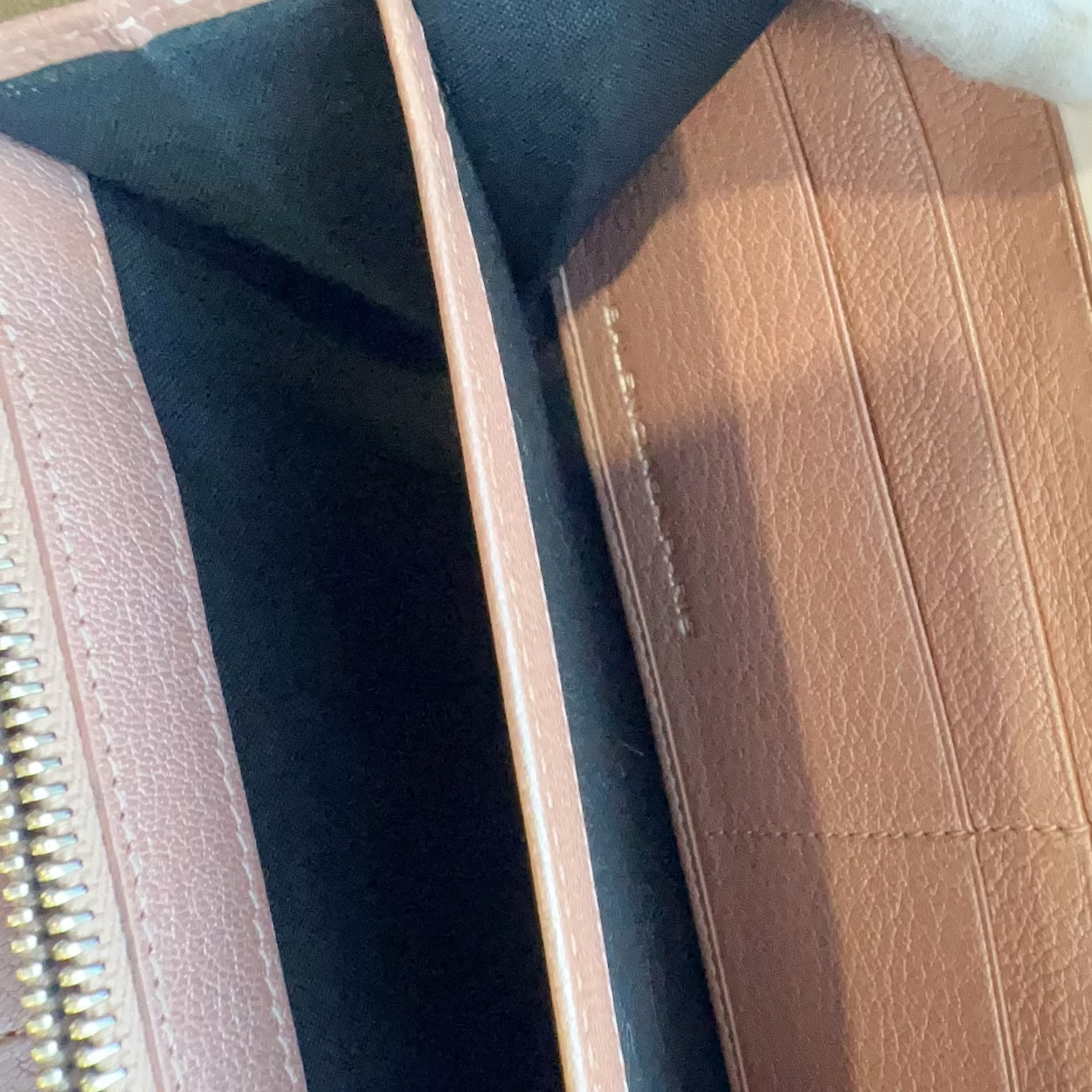 Close-up of a brown leather wallet with gold zipper and stitching detail.