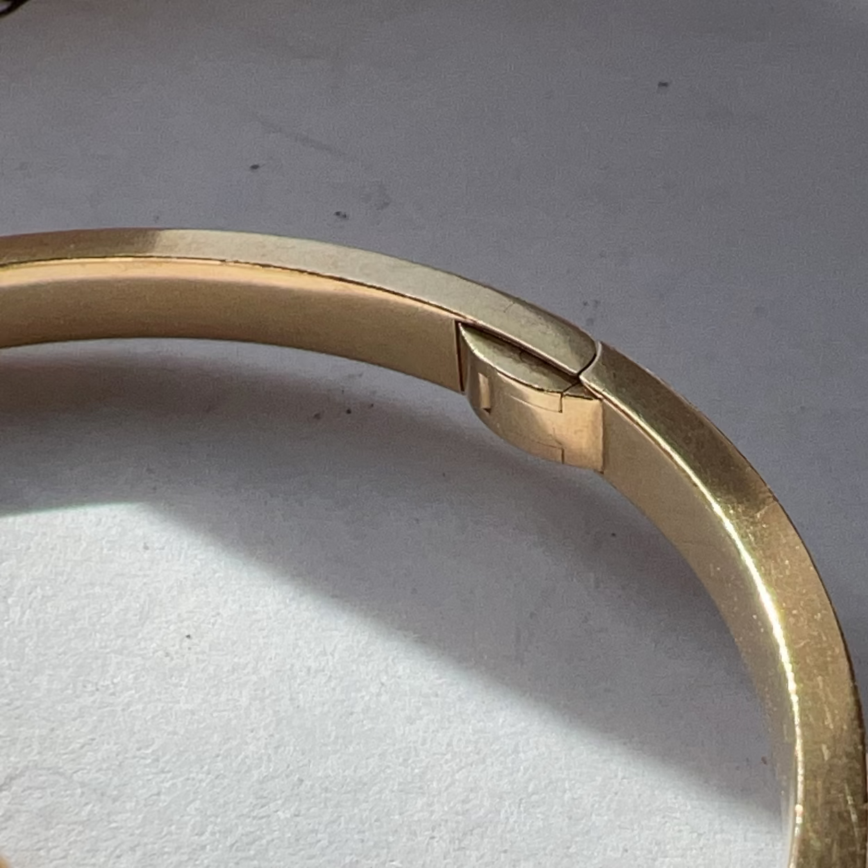 Gold bracelet on a light gray surface