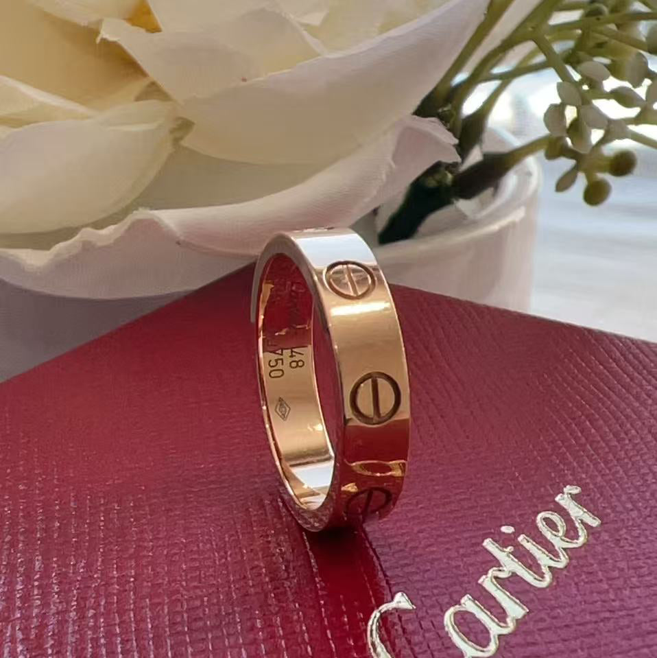 Rose gold Cartier ring on a red box with white flowers in the background