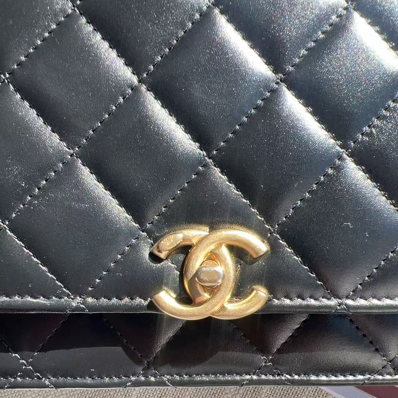 Black quilted handbag with gold Chanel logo on a Black surface