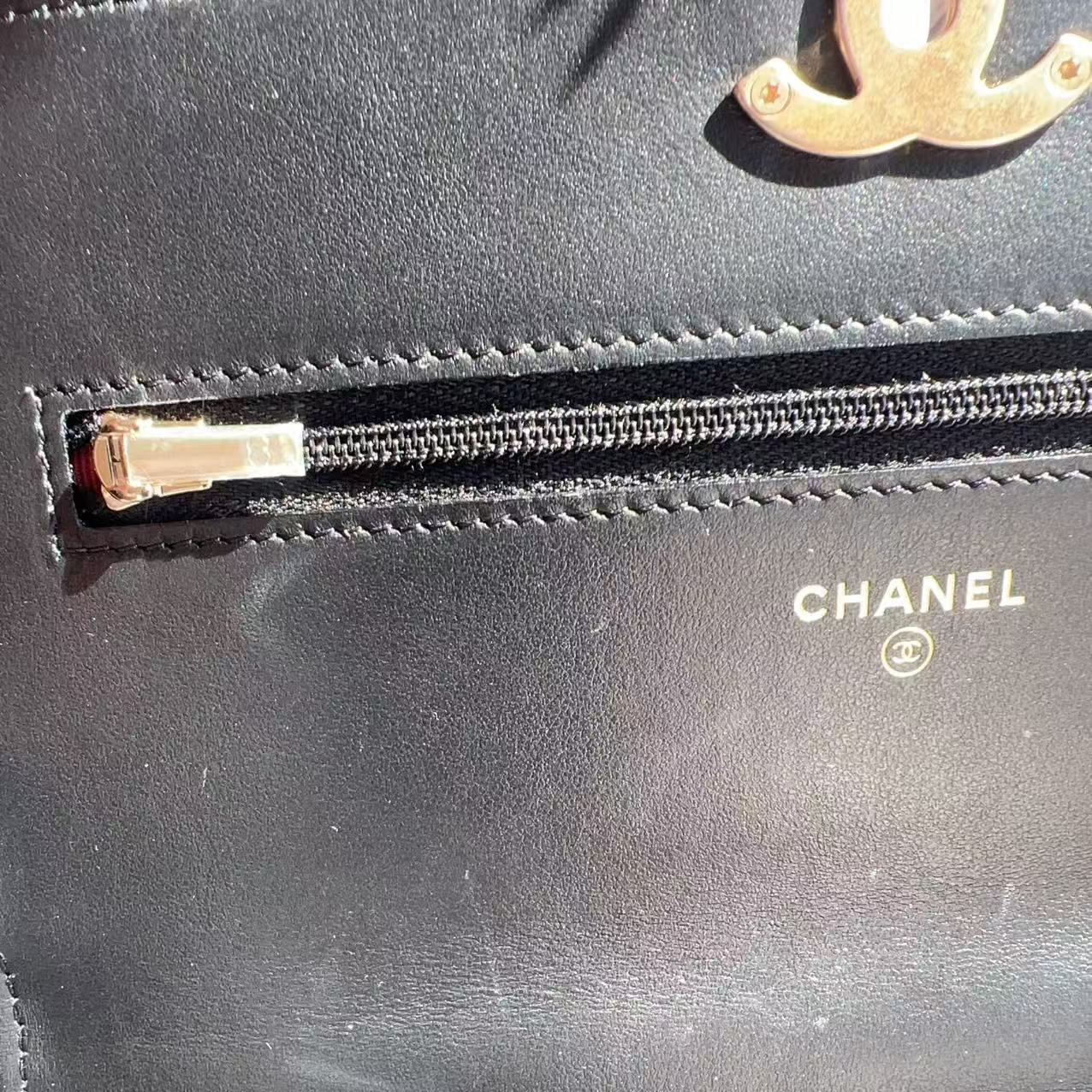 Close-up of a Chanel handbag with a gold zipper and visible branding.