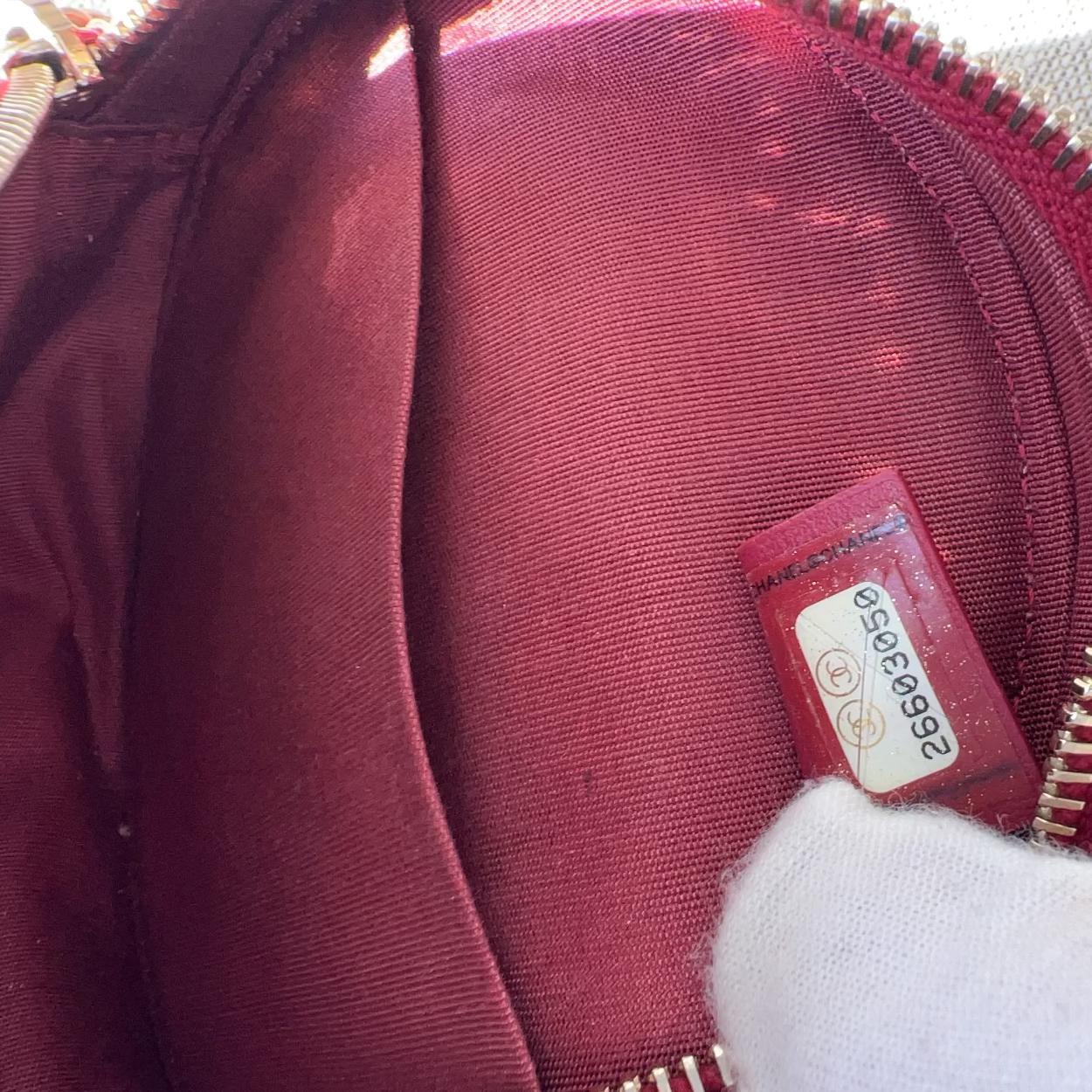 Close-up of a maroon bag with a visible brand label on a textured surface.