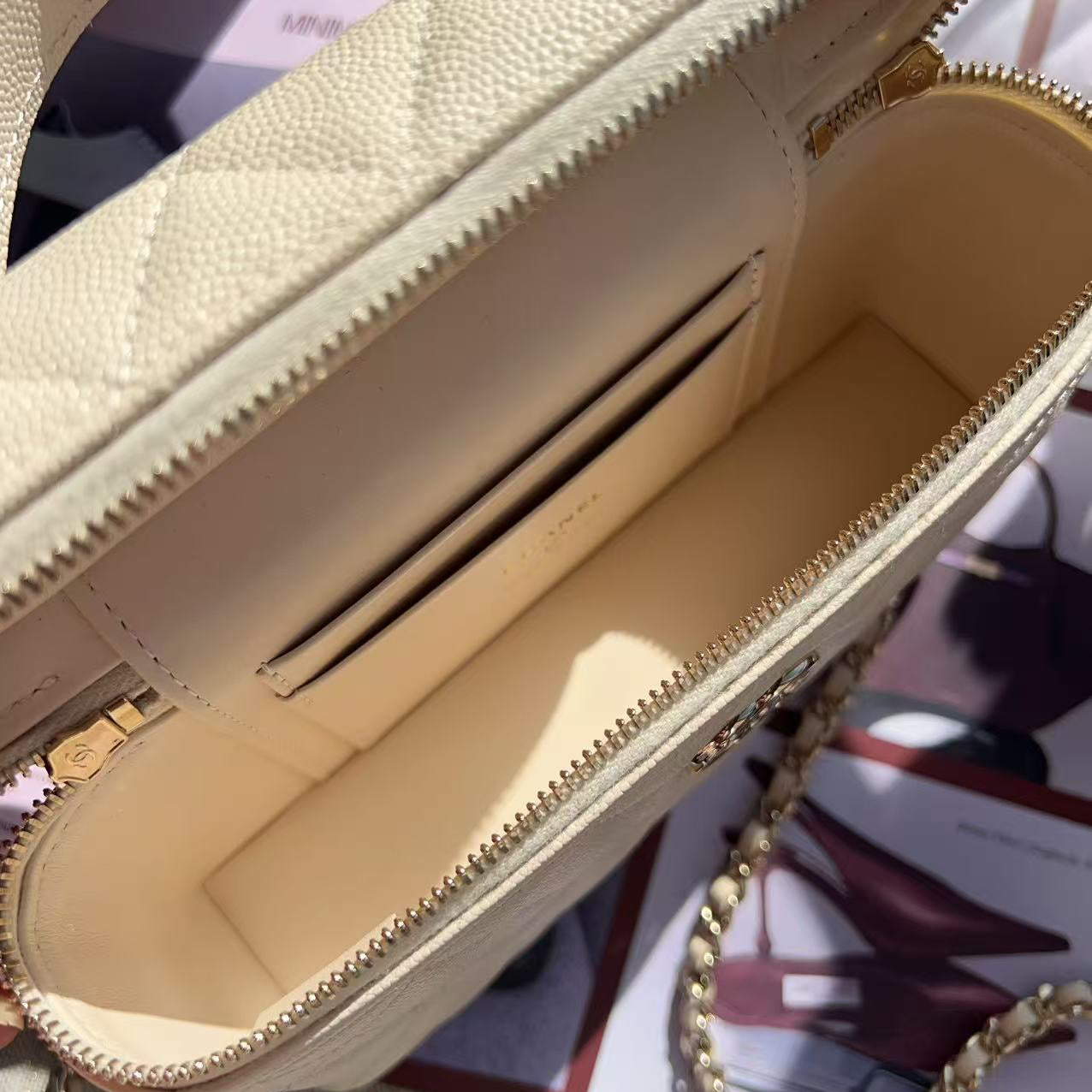 Close-up of a beige handbag with gold chain detail on a blurred background