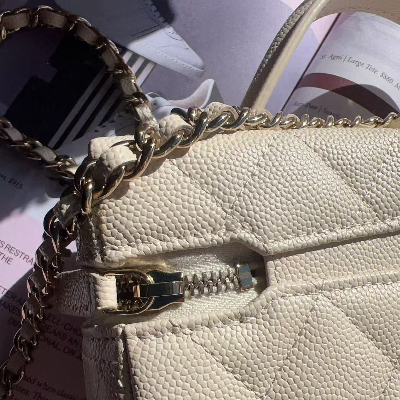 Close-up of a beige handbag with a gold chain strap