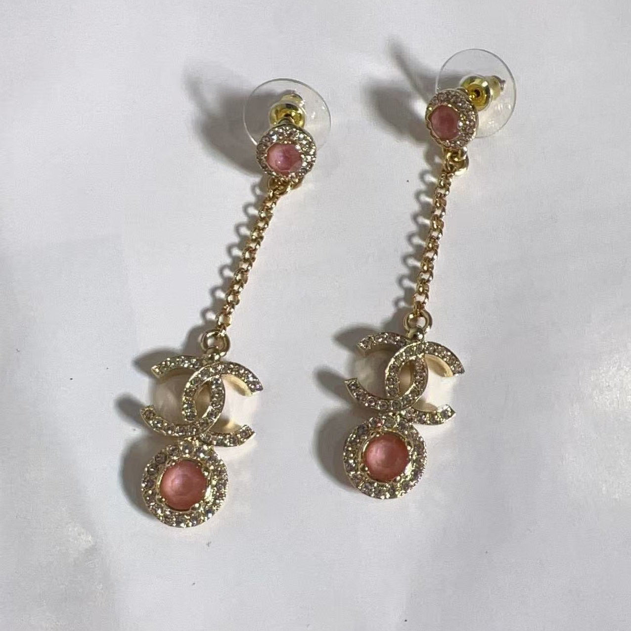 Pair of gold earrings with pink gemstones on a white background