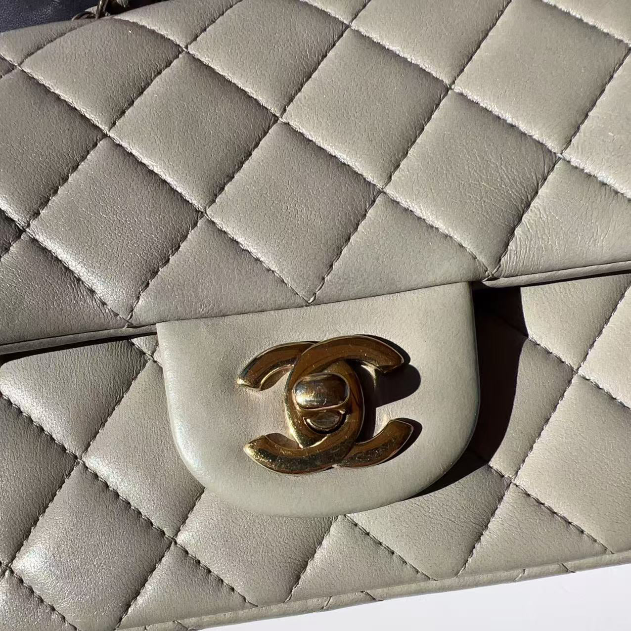 Close-up of a quilted handbag with a gold logo on a white background