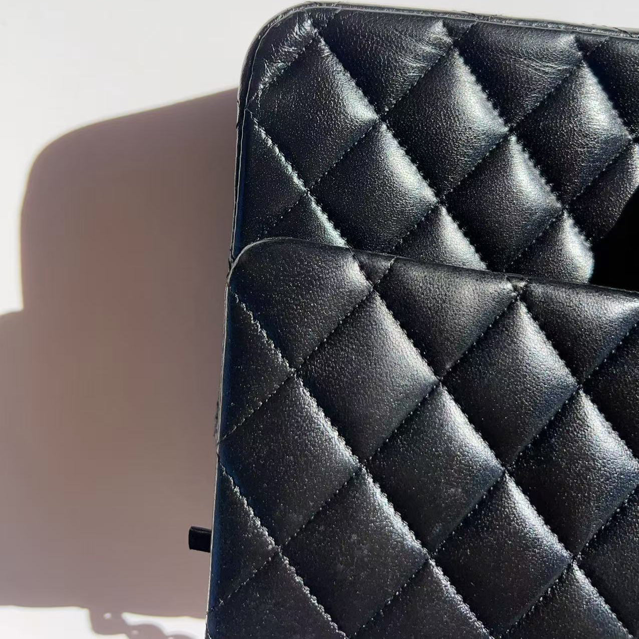 Black quilted leather bag on a light gray background