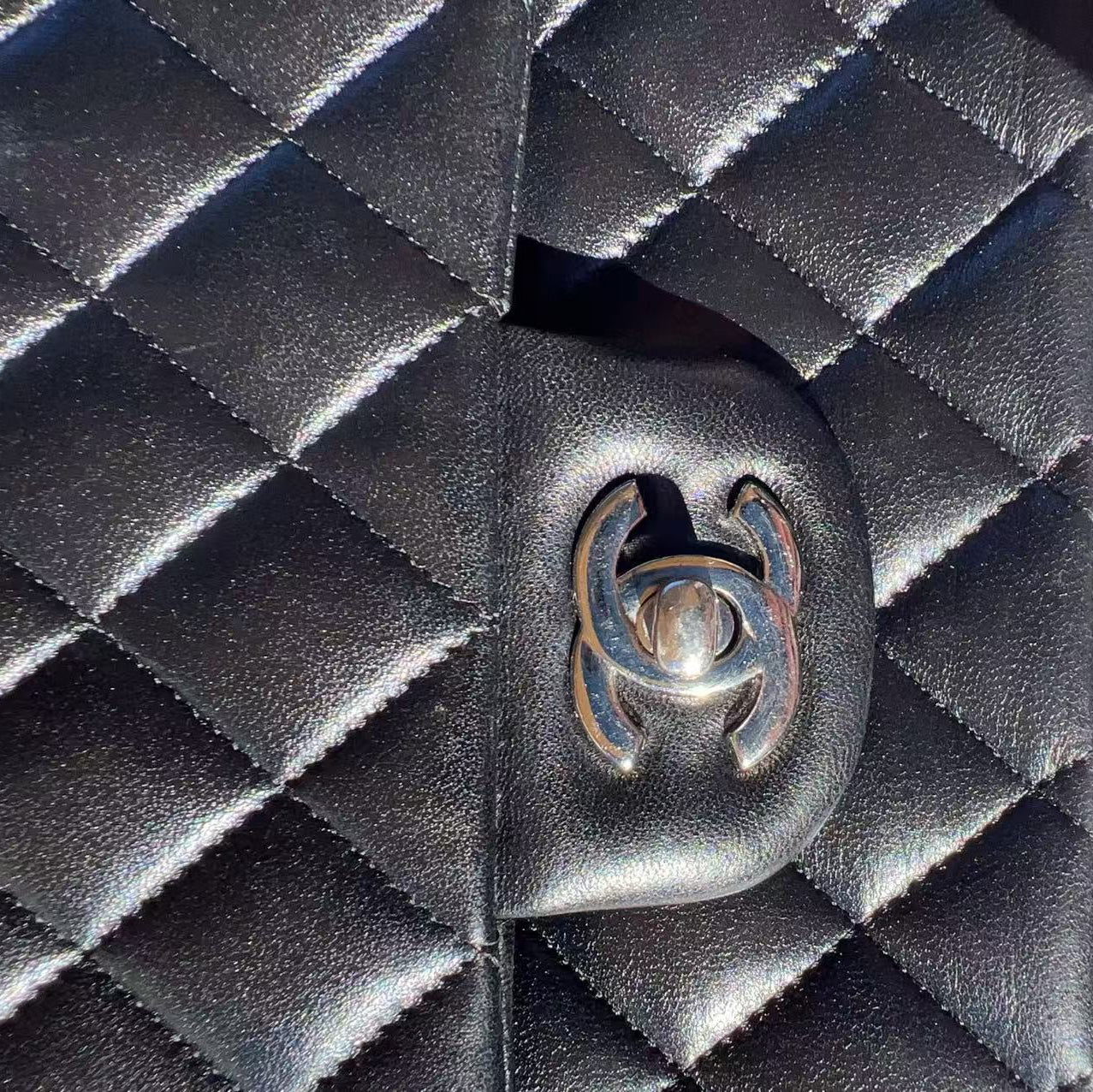 Close-up of a Chanel handbag with diamond quilted design and logo.