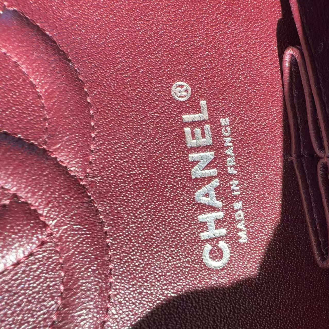 Close-up of a Chanel logo on a red leather product.