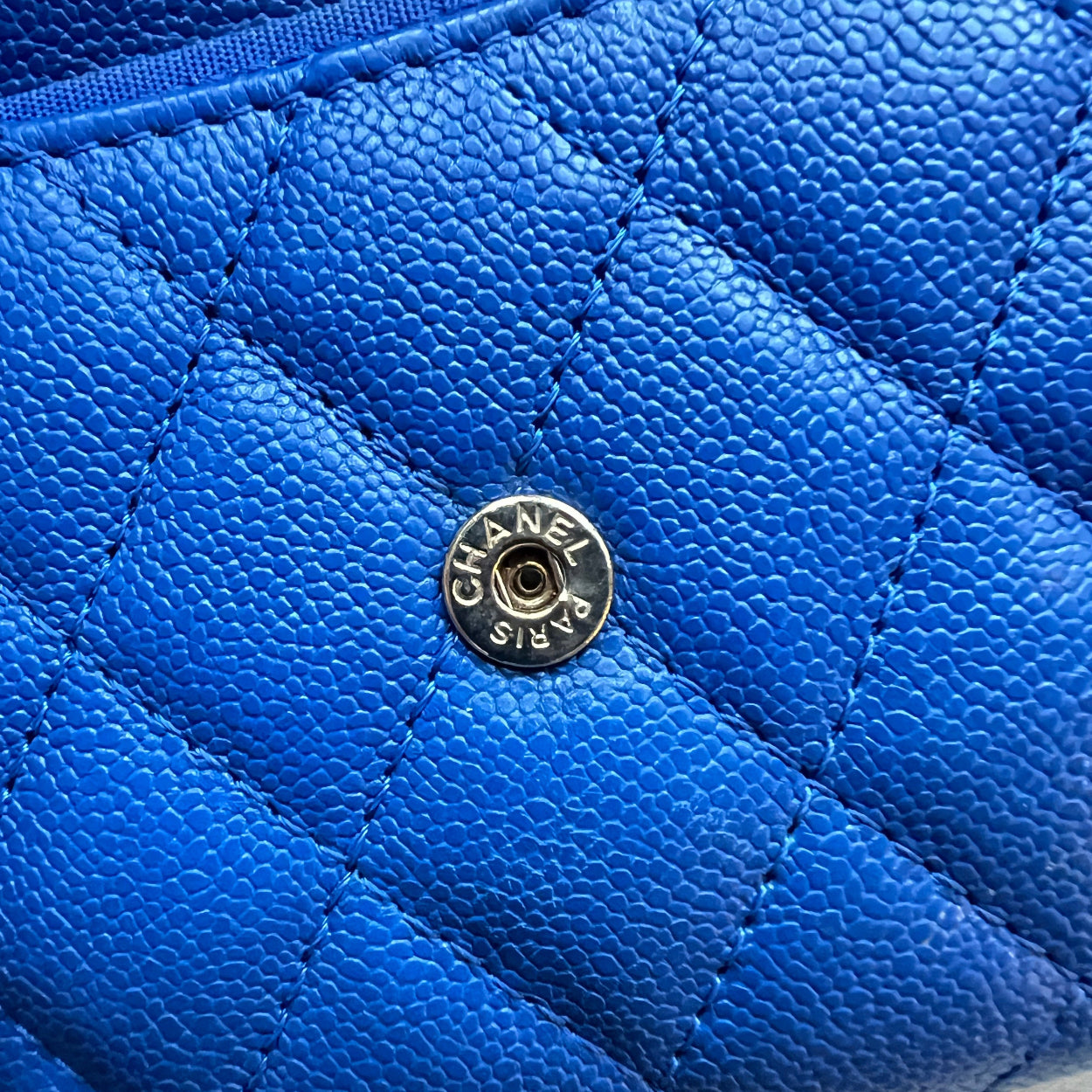 Close-up of a blue quilted handbag with a Chanel logo.