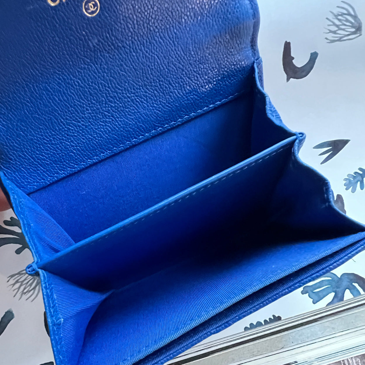 Blue wallet being held open with a patterned surface in the background