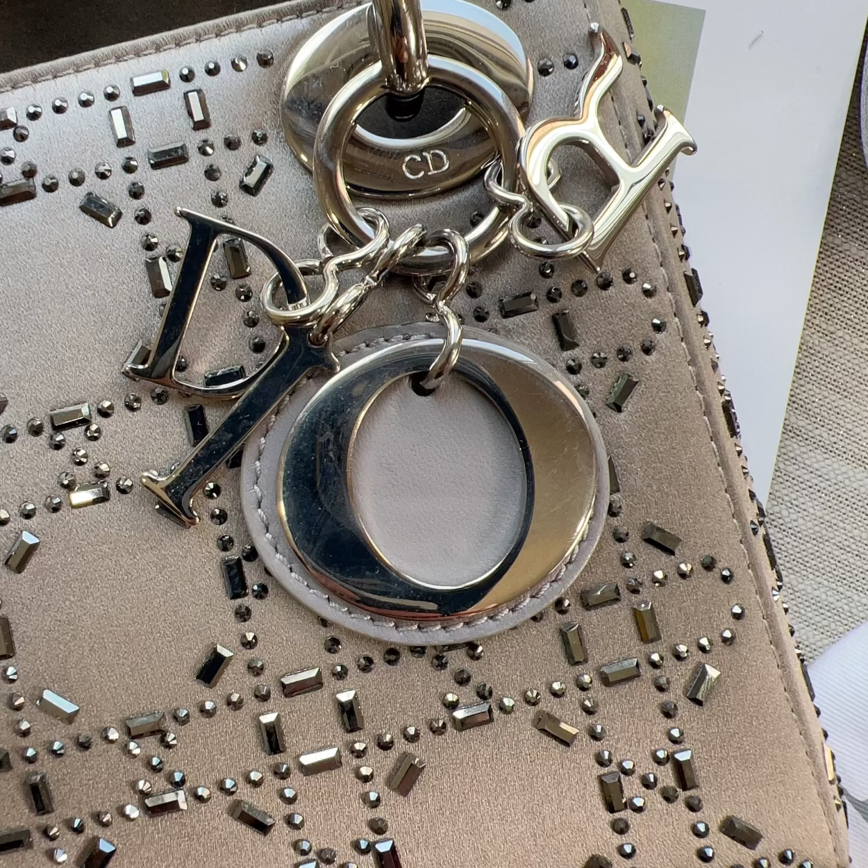 Studded handbag with a keychain featuring 'CD' initials on a neutral background