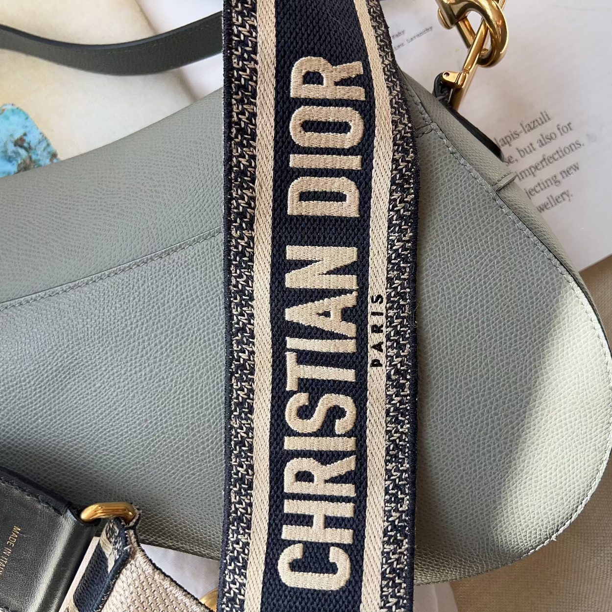 Gray handbag with a Christian Dior strap on a light surface.