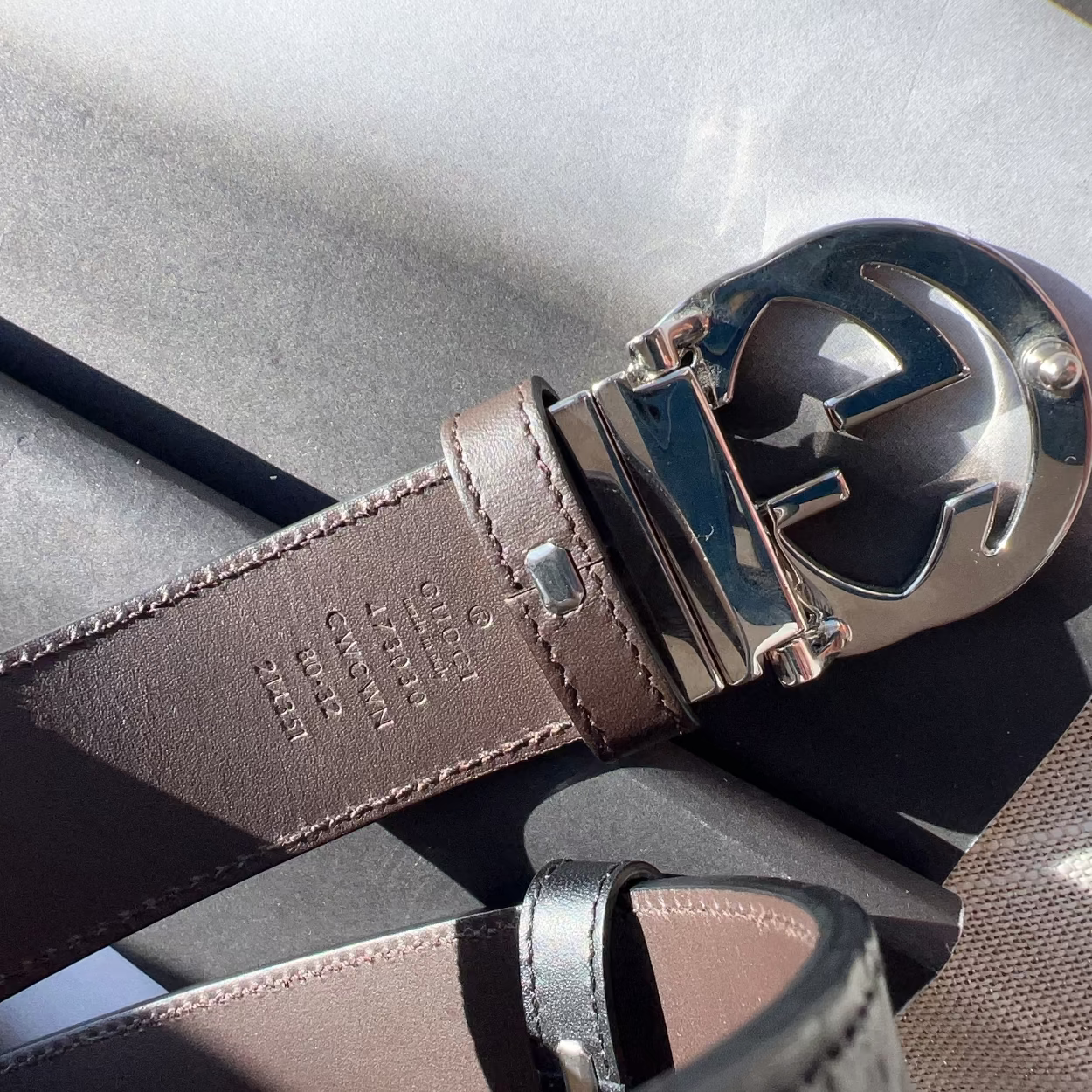 Brown leather belt with silver anchor buckle on a textured surface