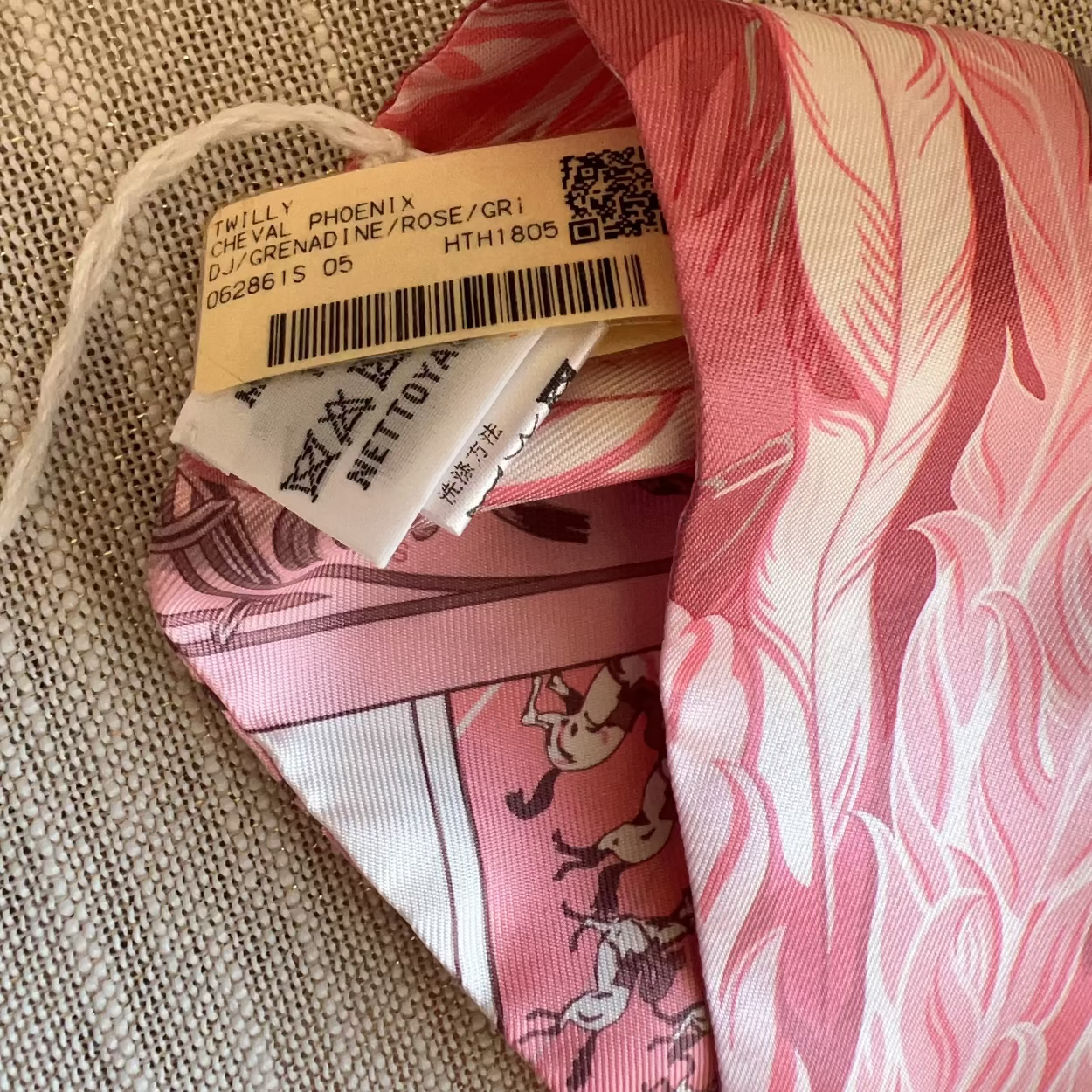 Pink fabric with a pattern and a visible brand tag on a beige surface