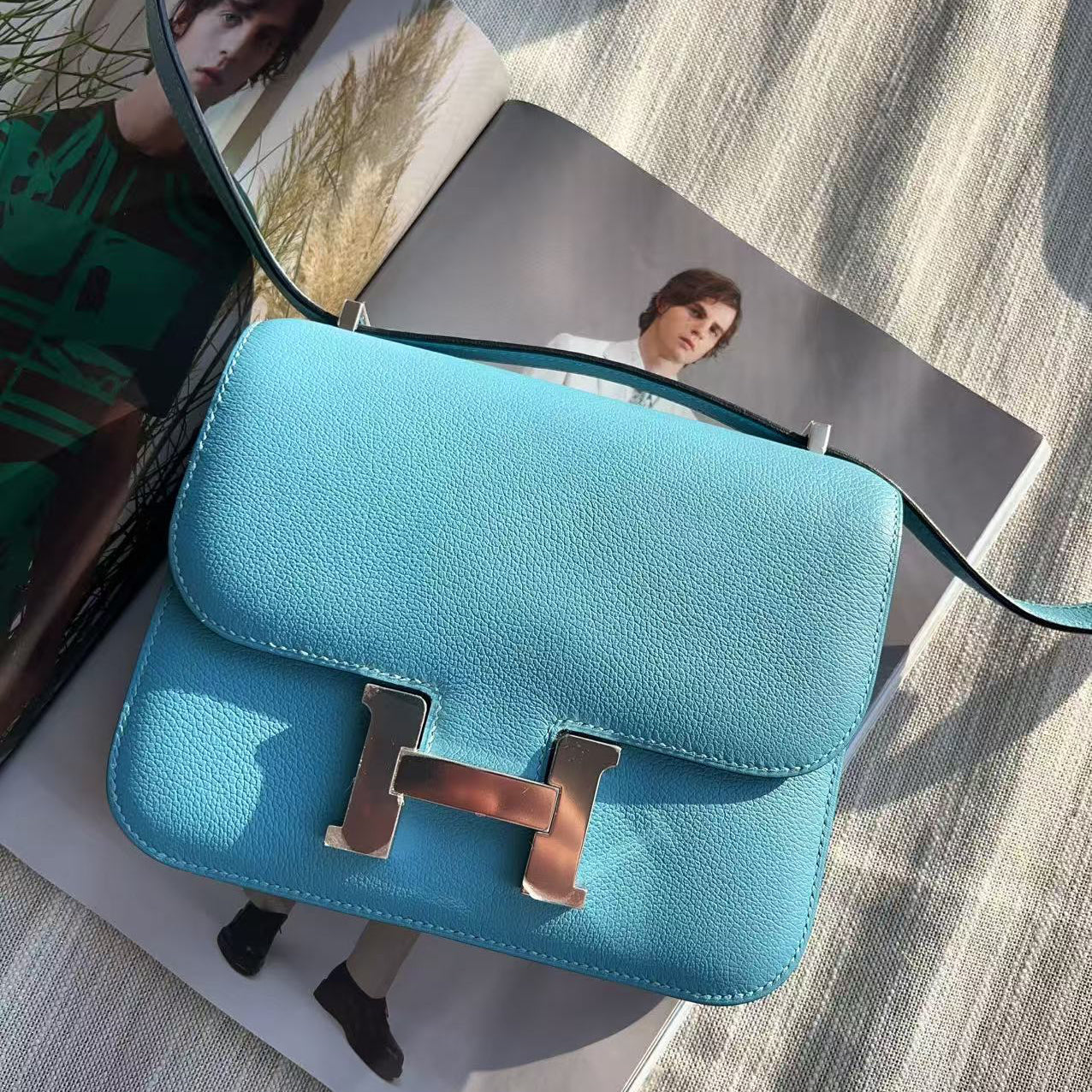 Blue handbag with gold hardware on a textured surface