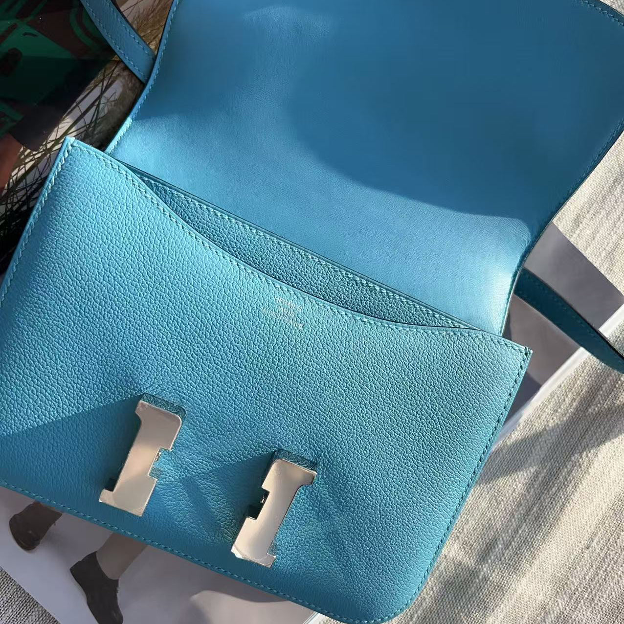 Blue handbag with silver clasp on a textured surface