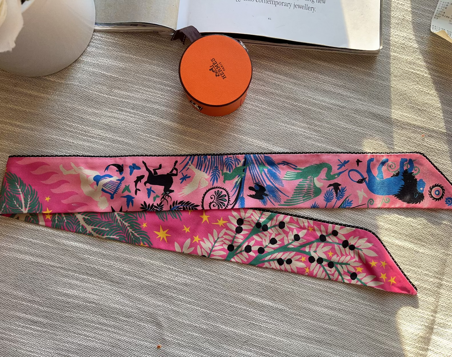 Colorful headband with animal designs on a wooden surface next to a small round container.