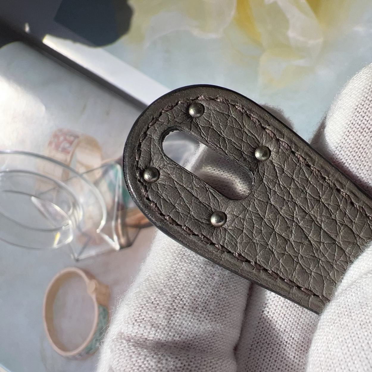 Close-up of a brown leather keychain with metal clasps on a light fabric background.