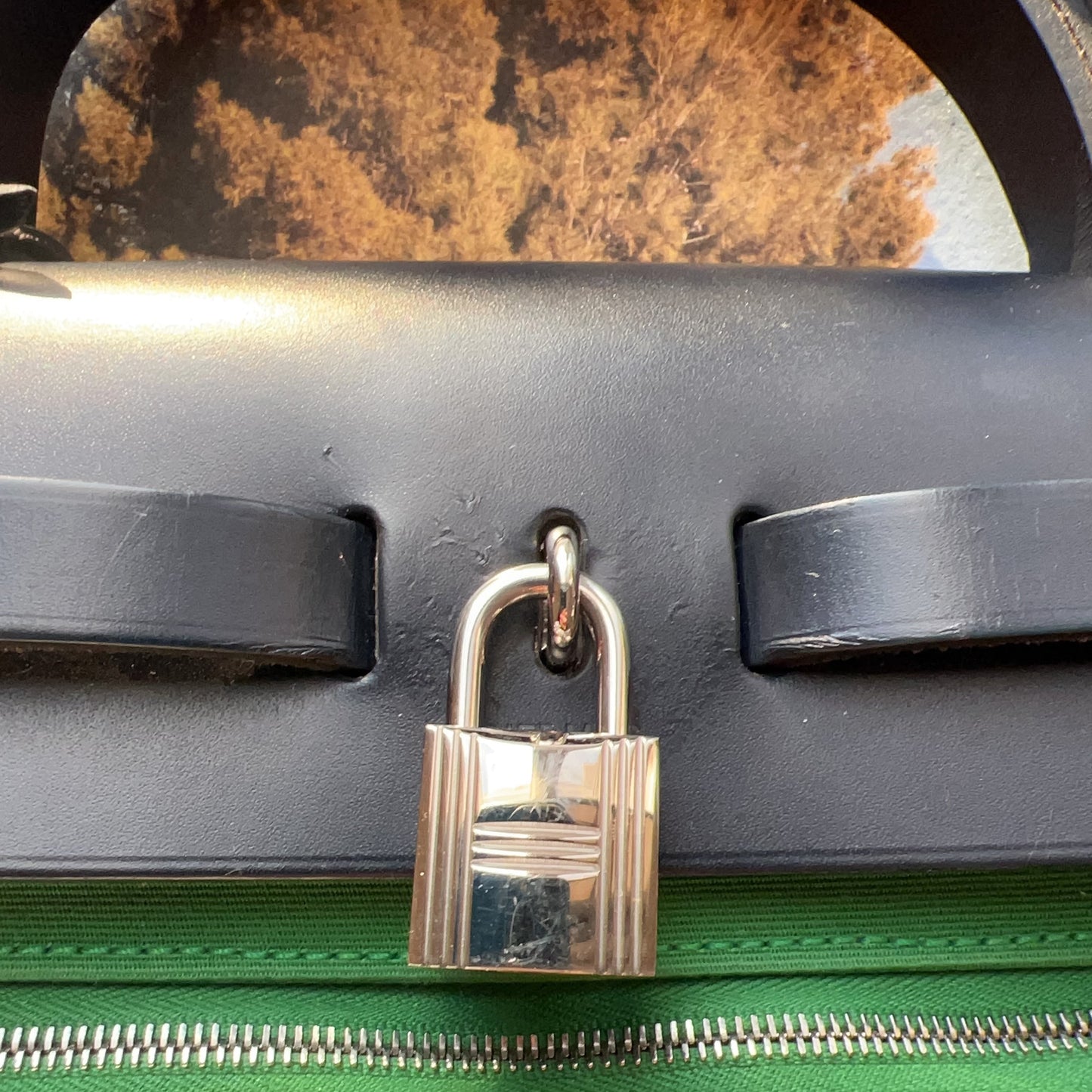 Green suitcase with a silver lock on a blurred natural background