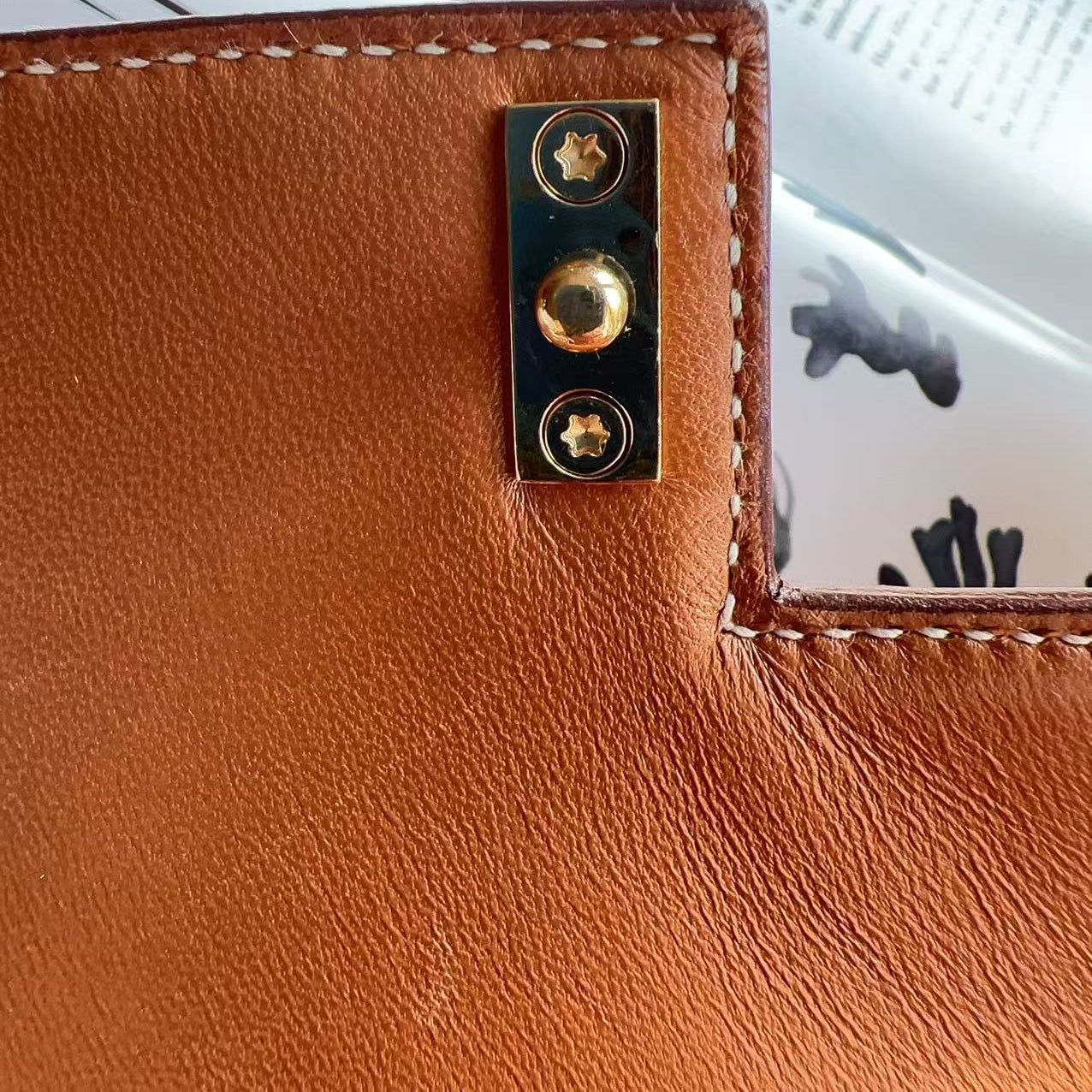 Close-up of a brown leather wallet with gold hardware