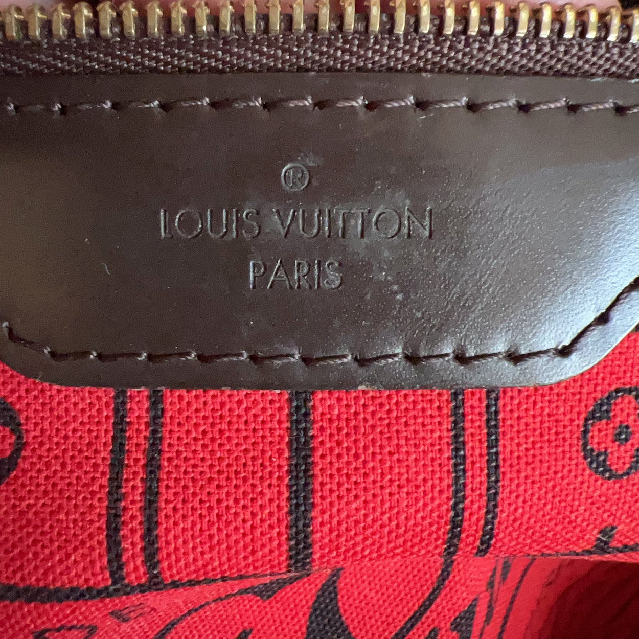 Close-up of a Louis Vuitton bag with red fabric and black design, featuring the brand logo.
