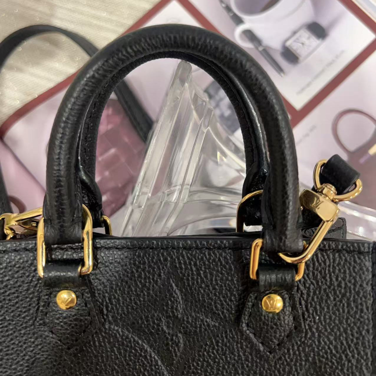 Black handbag with gold accents on a light wooden surface