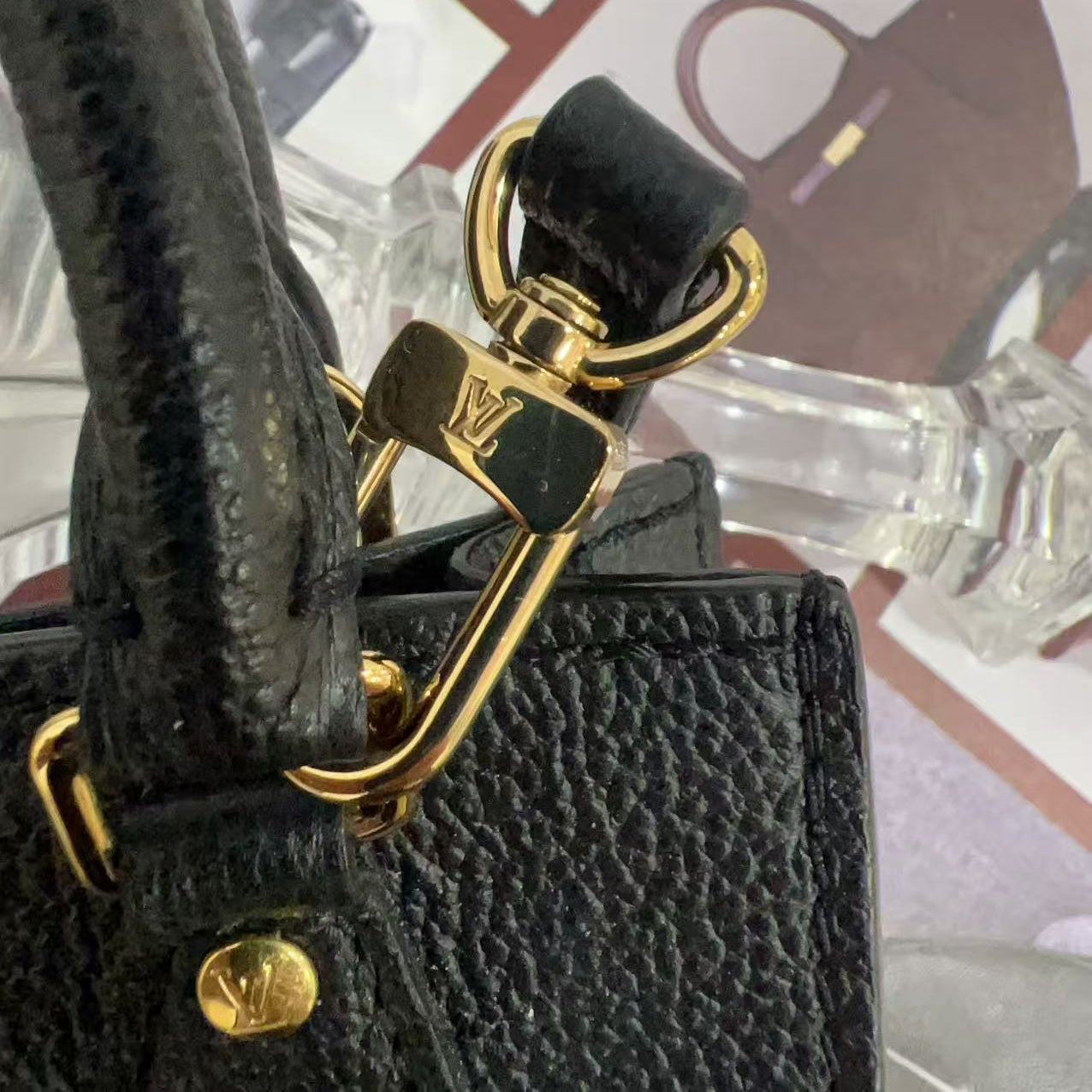 Close-up of a black handbag handle with gold hardware against
