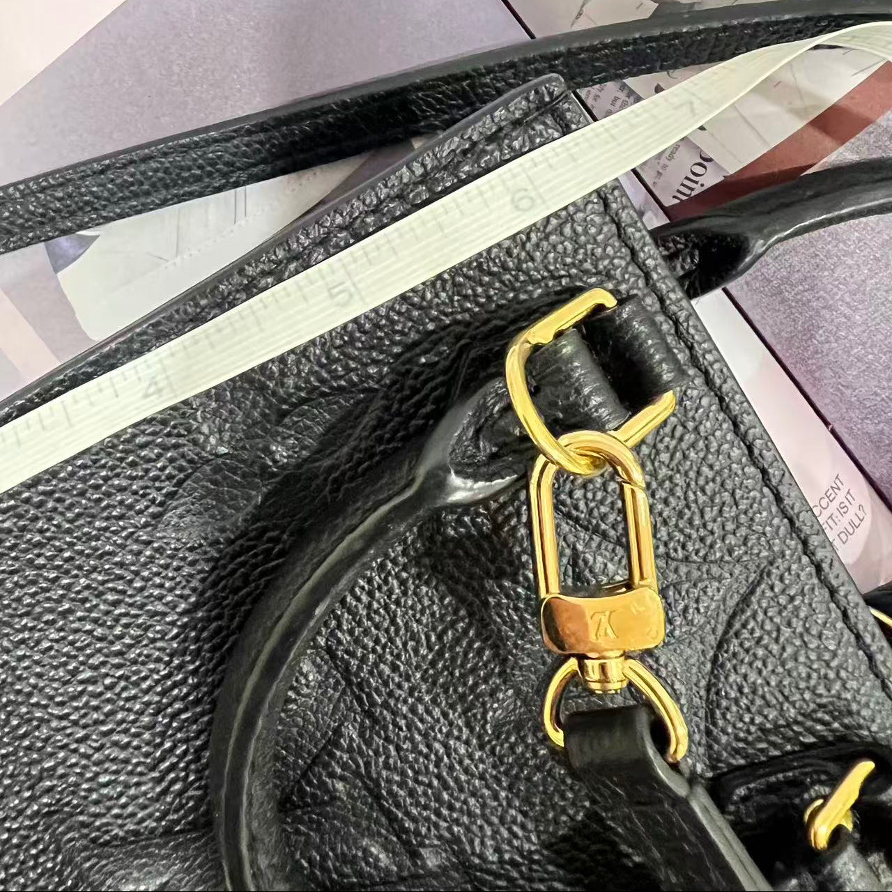 Black leather handbag with gold clasp on a surface