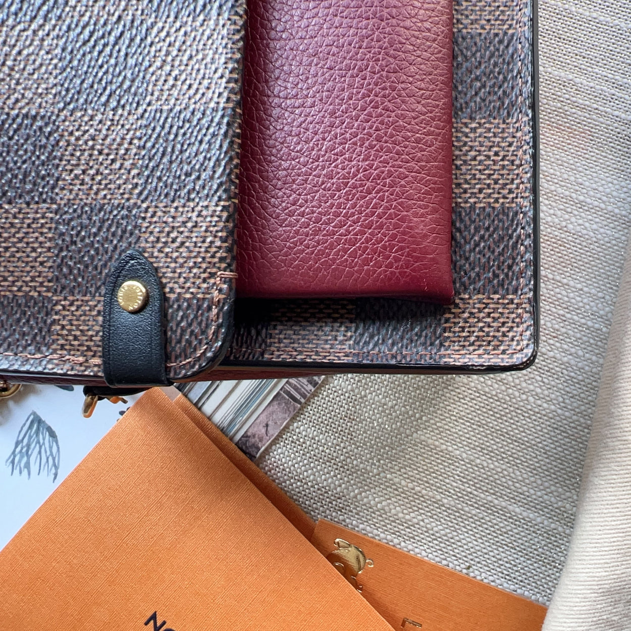 Close-up of a textured wallet and orange book on a checkered fabric background