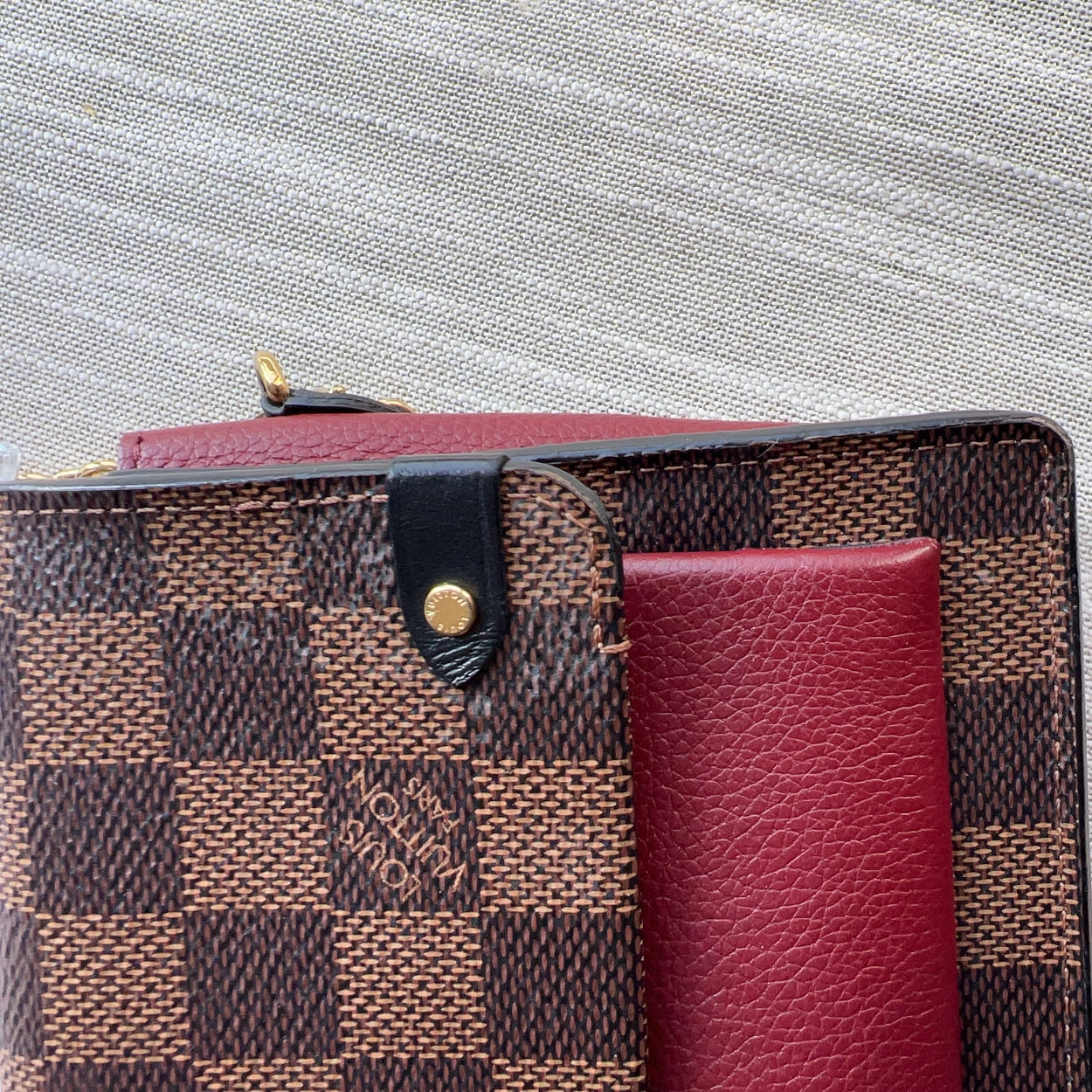 Designer wallet with checkered pattern and red interior on a textured surface