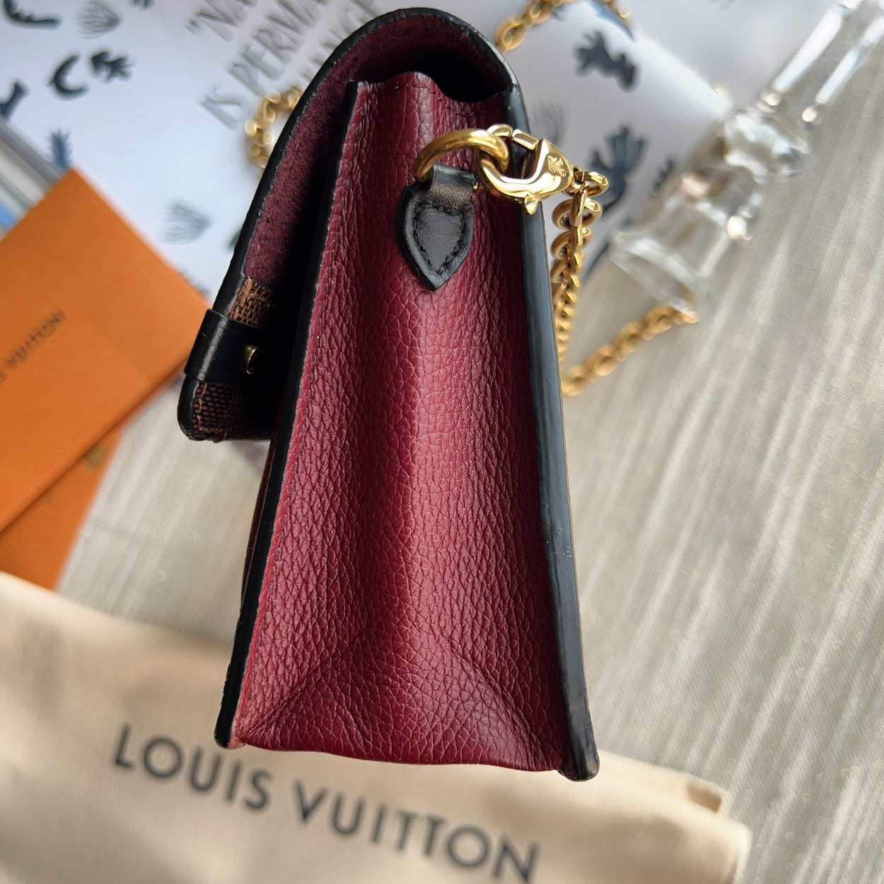 Red leather pouch with gold chain on a Louis Vuitton bag