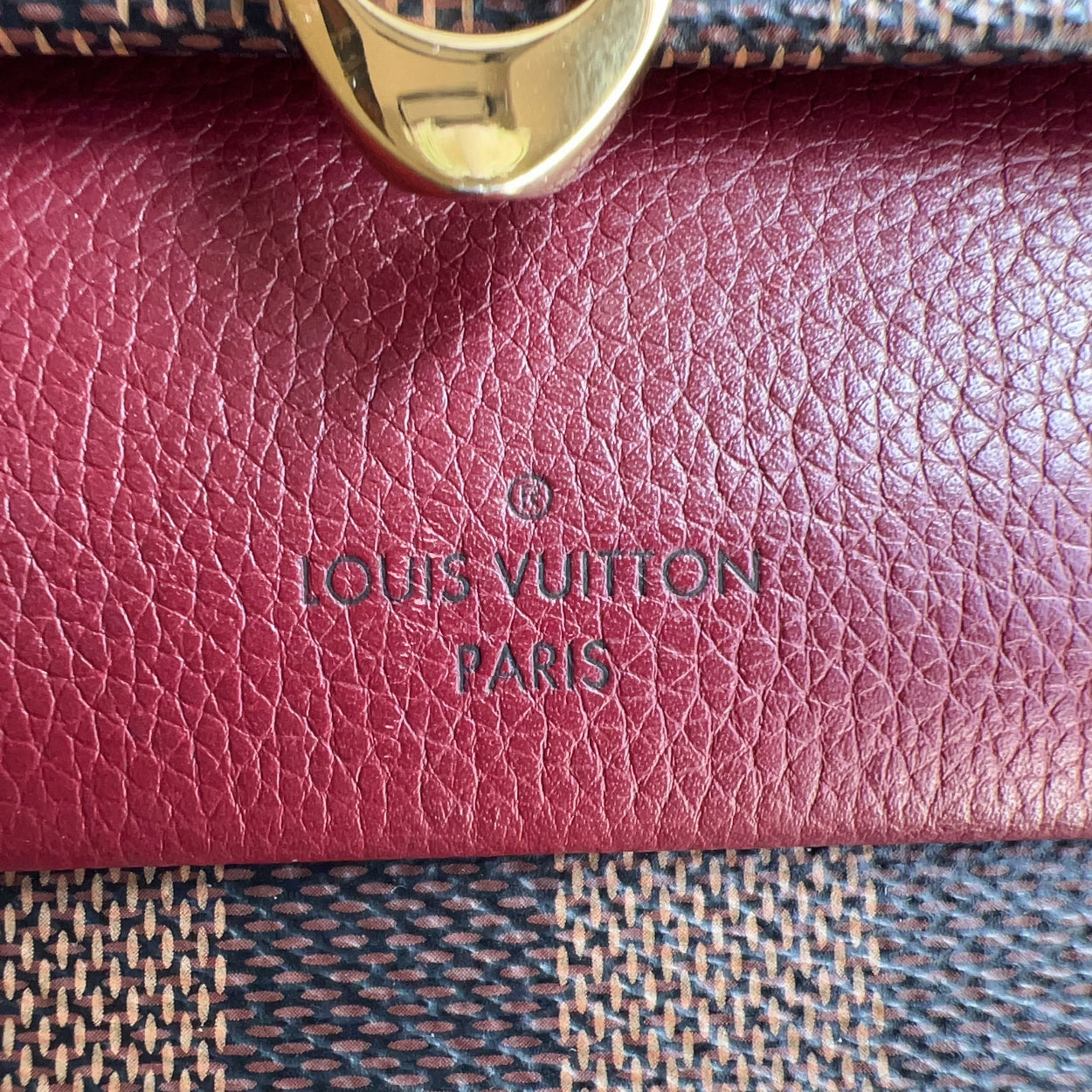 Close-up of a Louis Vuitton wallet with gold ring on a patterned fabric background