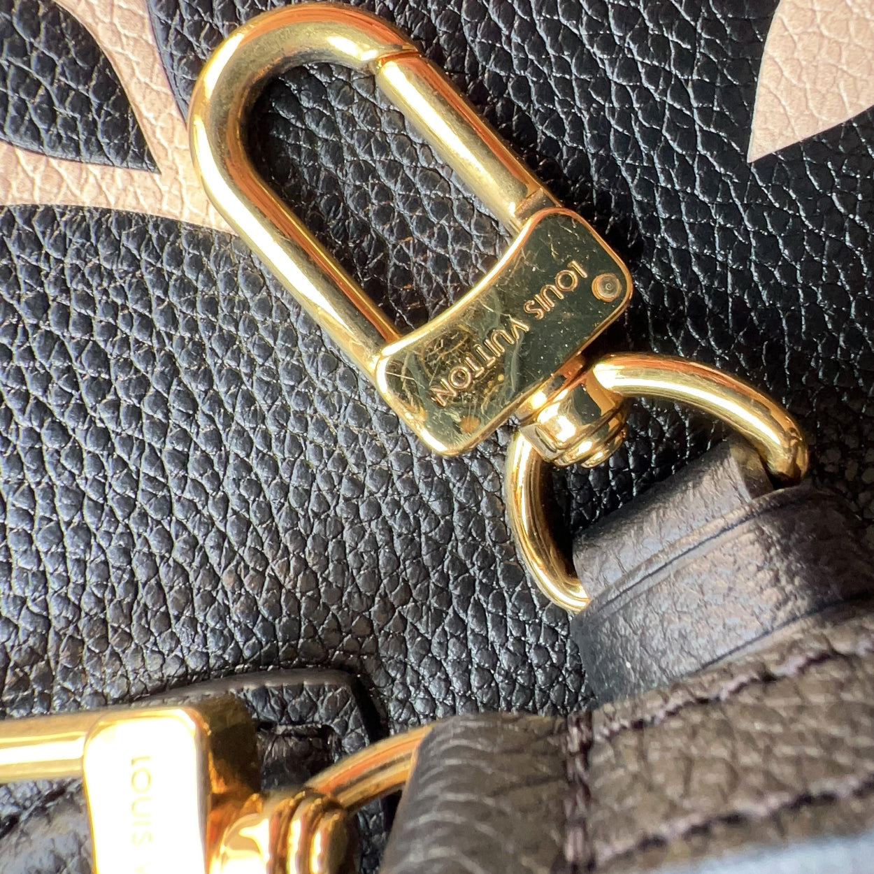 Close-up of a gold lock on a leather bag with visible brand name.