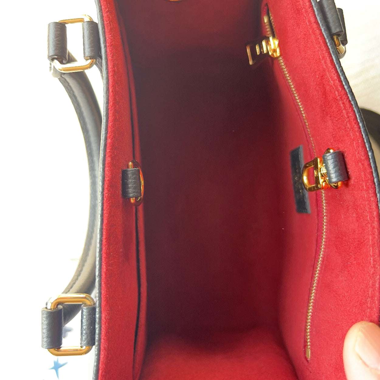 Close-up of a red handbag with gold and black hardware.