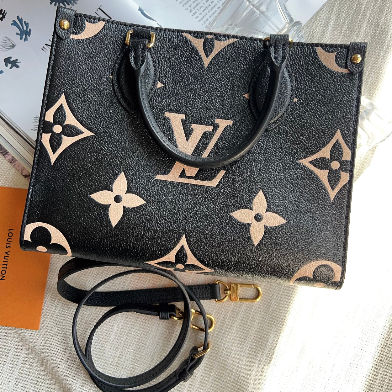 Black handbag with beige monogram pattern on a light surface