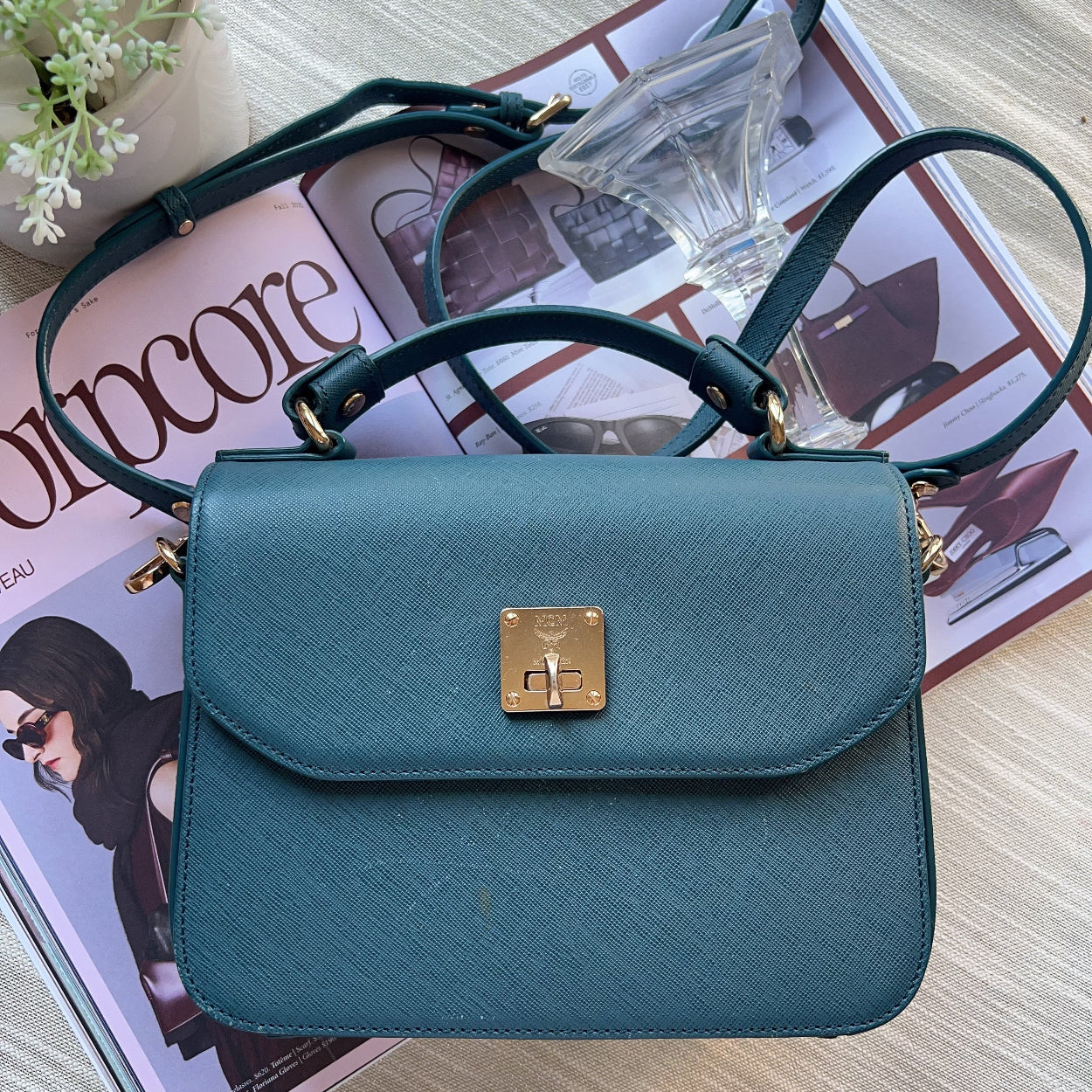 Teal handbag with gold clasp on a magazine