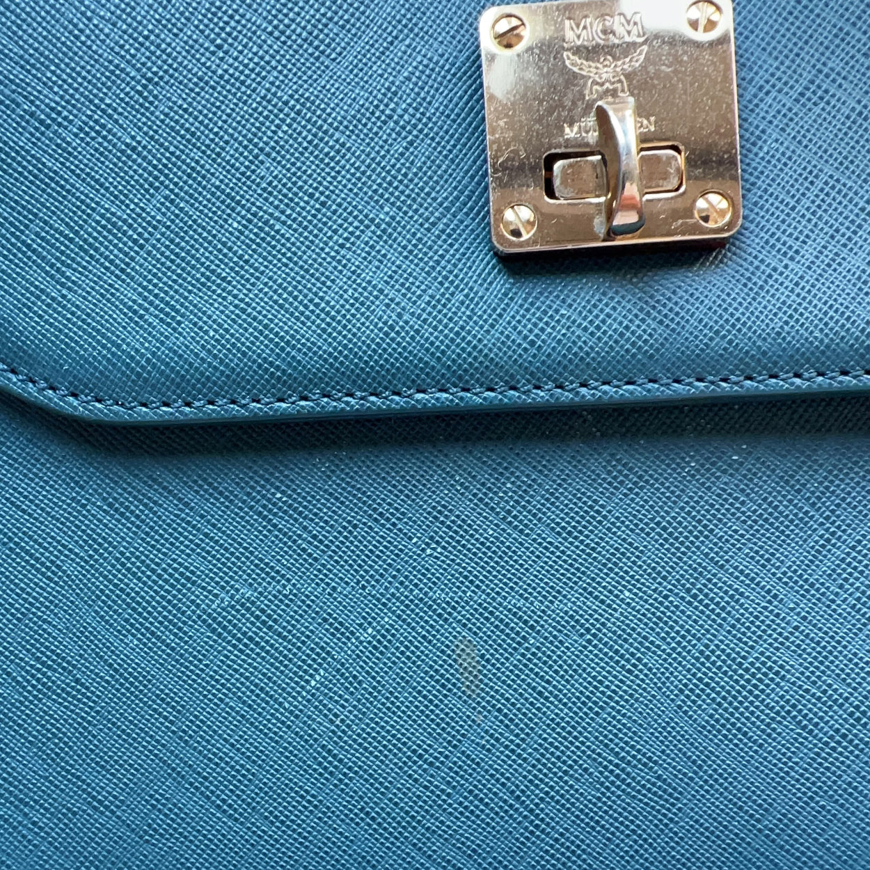 Blue handbag with a gold logo on a blue background