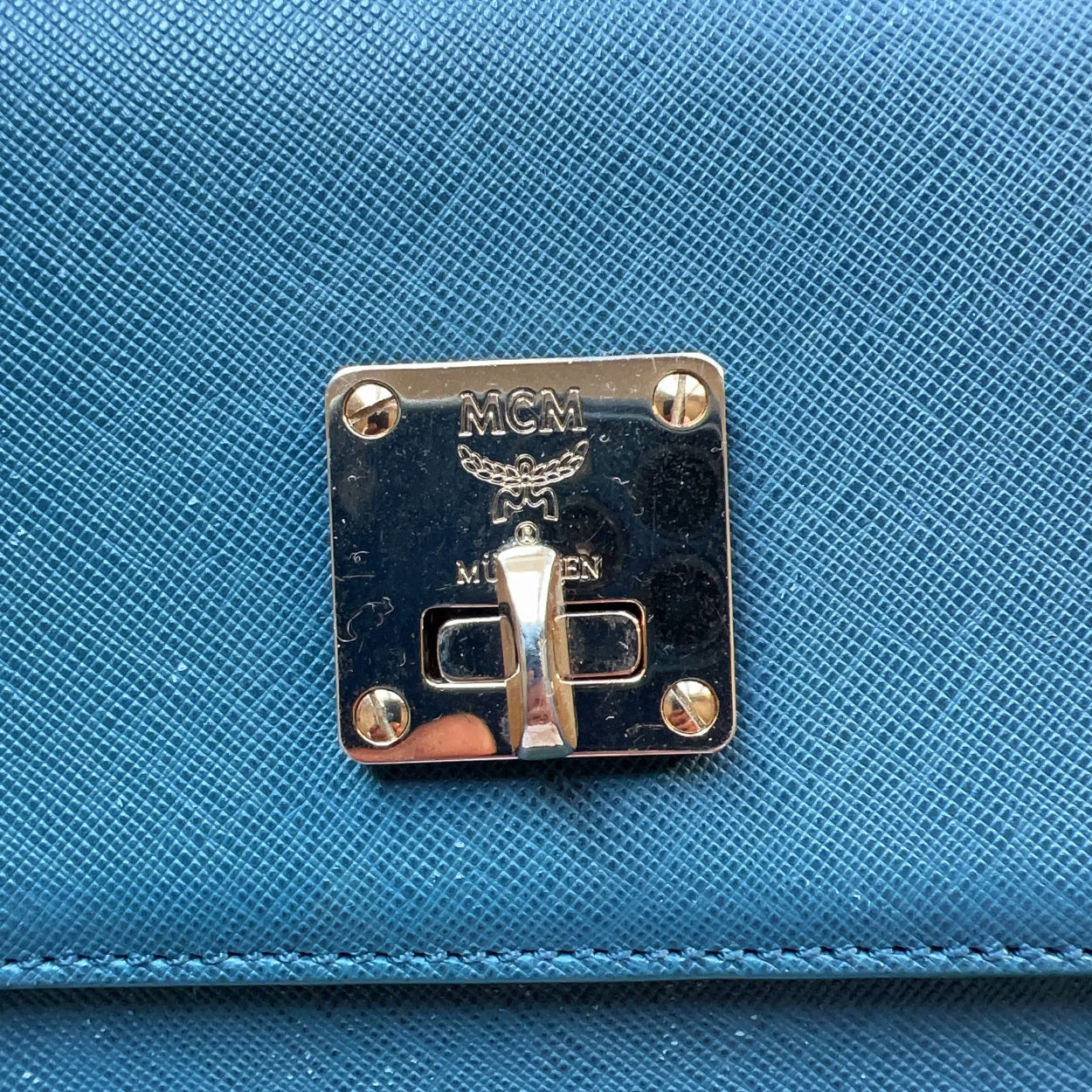Blue handbag with a gold logo on a white background