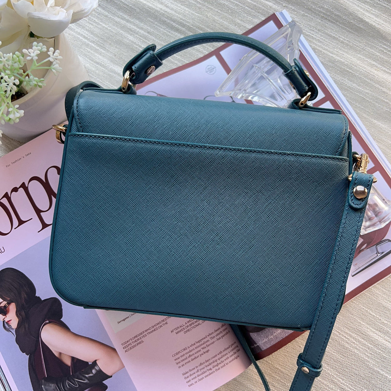 Teal handbag on a magazine with a blurred background