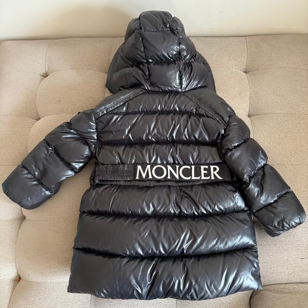 Black Moncler puffer jacket on a beige sofa
