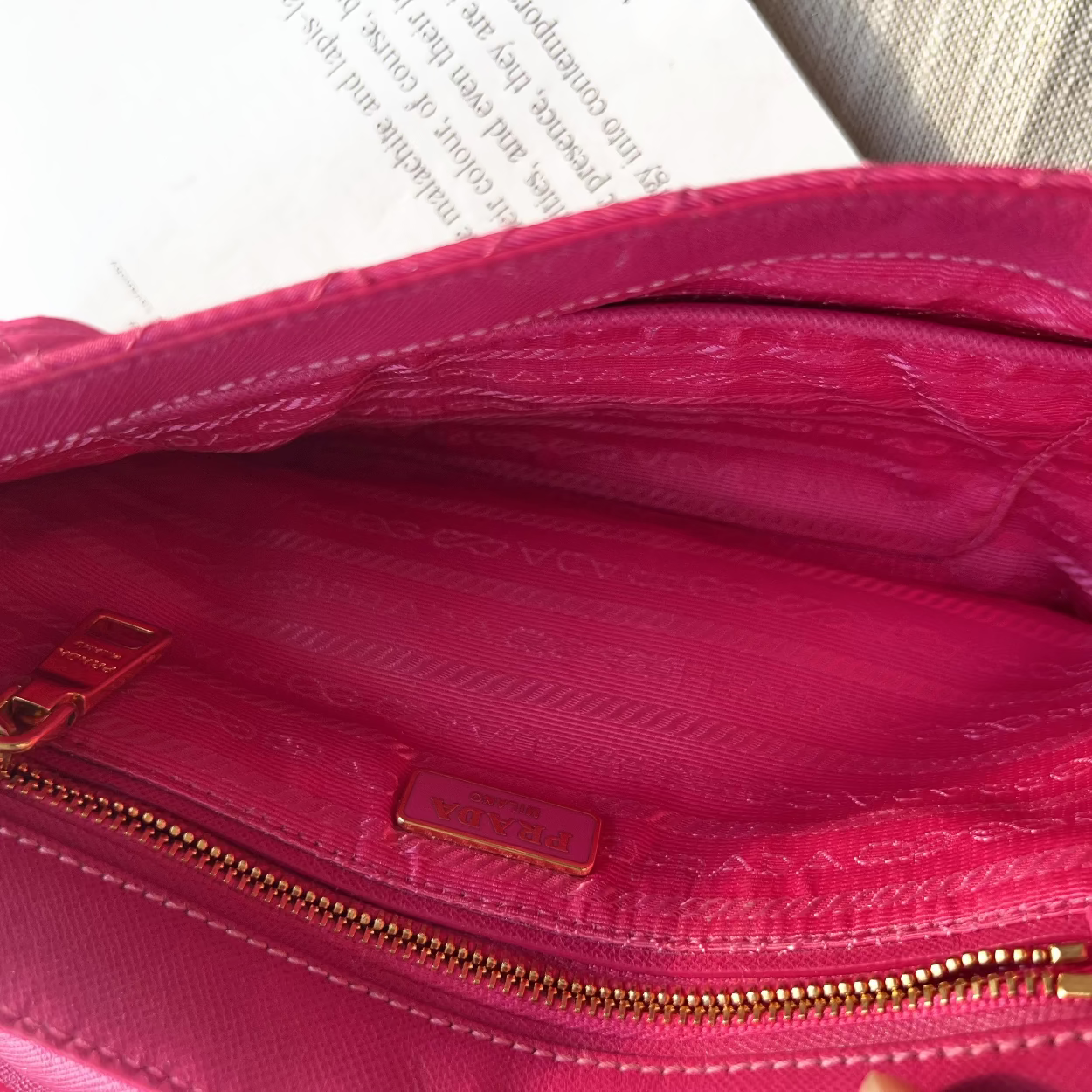 Close-up of a pink handbag with a gold zipper and visible brand logo.
