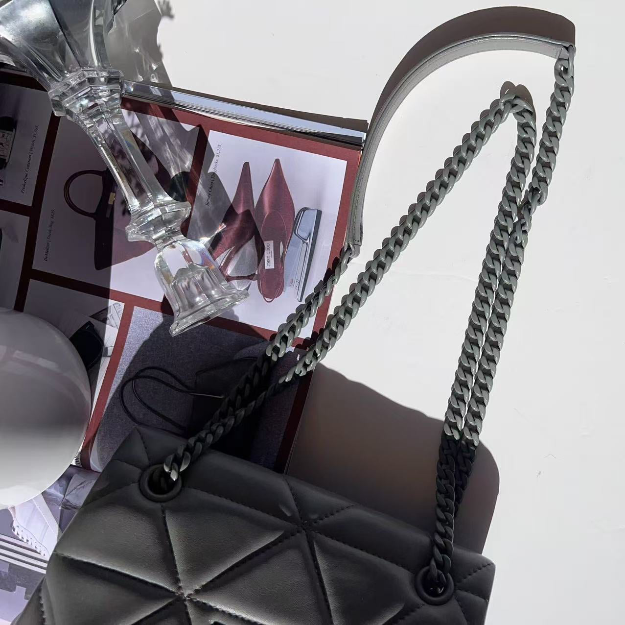 Black handbag with chain handle on a white surface
