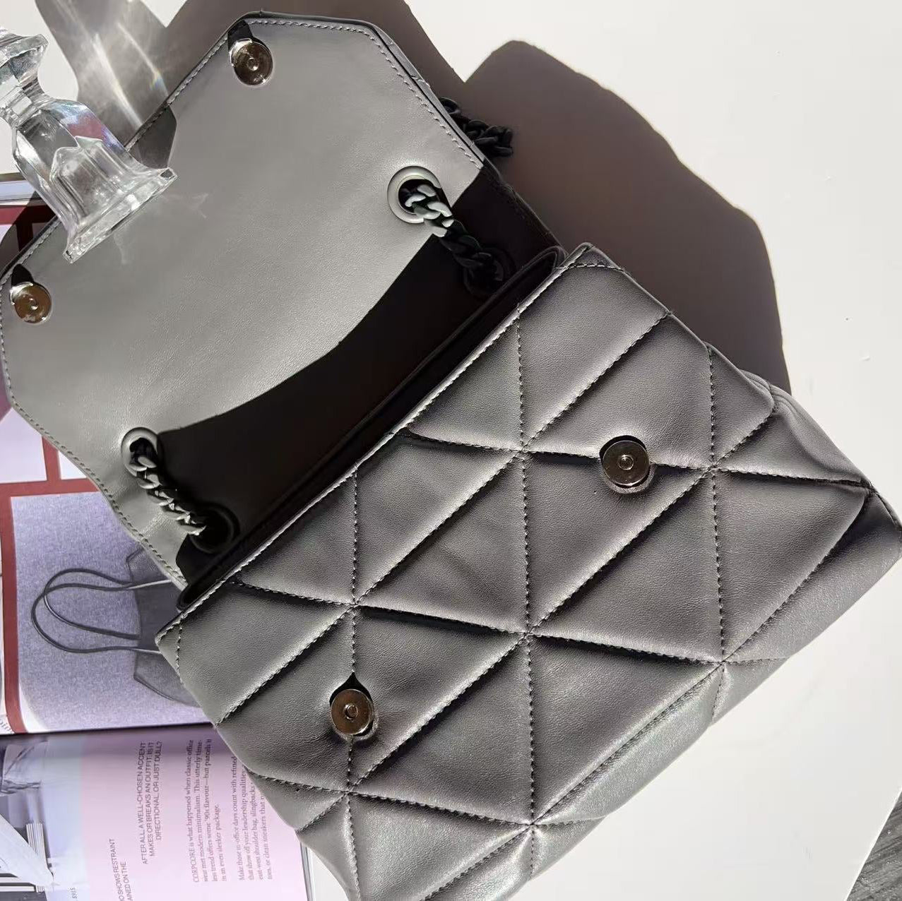 Gray quilted handbag with gold accents on a light background