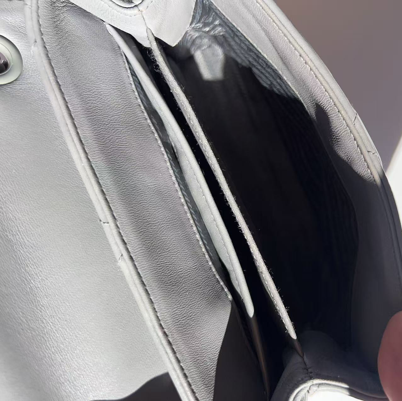 Close-up of a hand holding a silver clutch bag with a blurred background