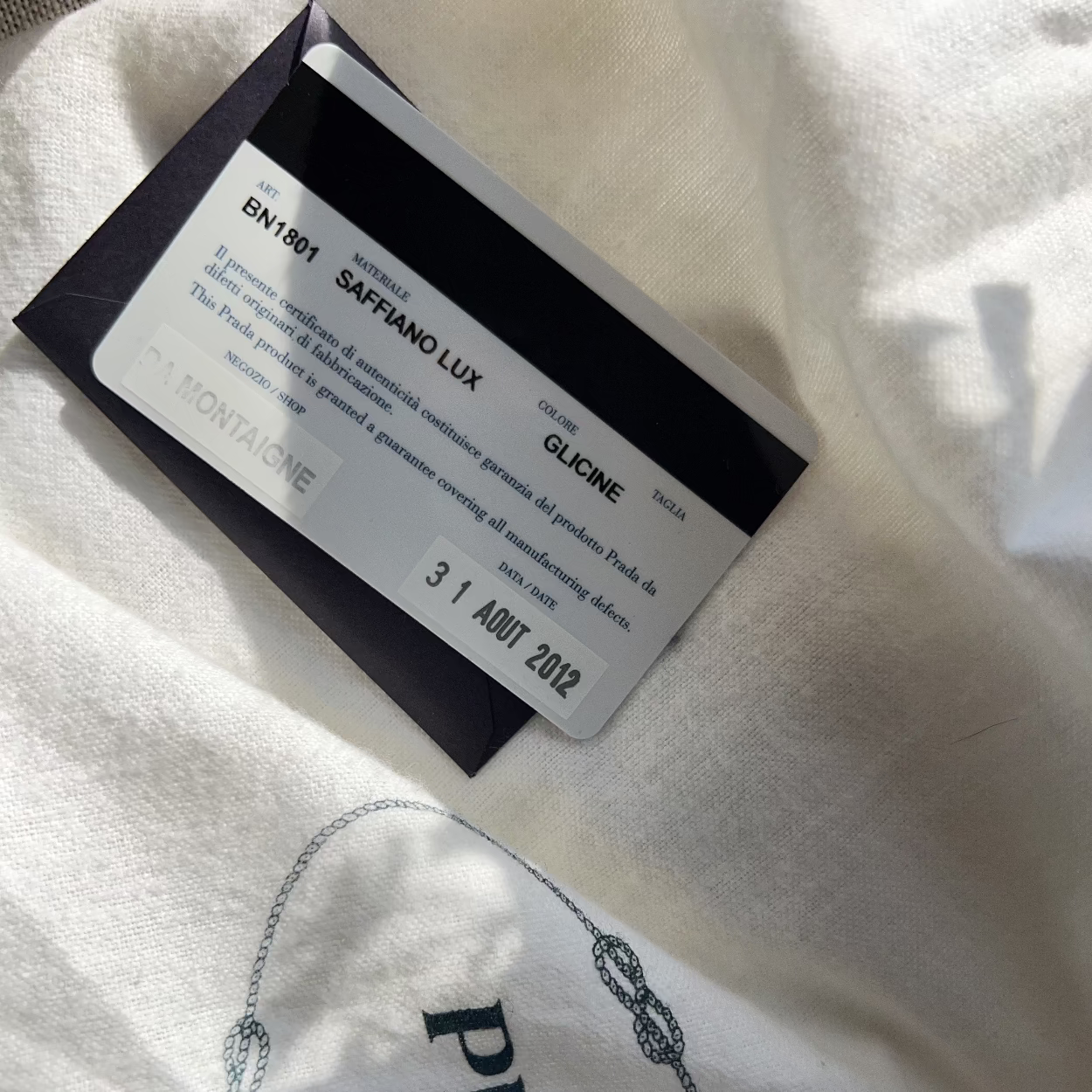 Close-up of a Prada garment with a tag on a white fabric background